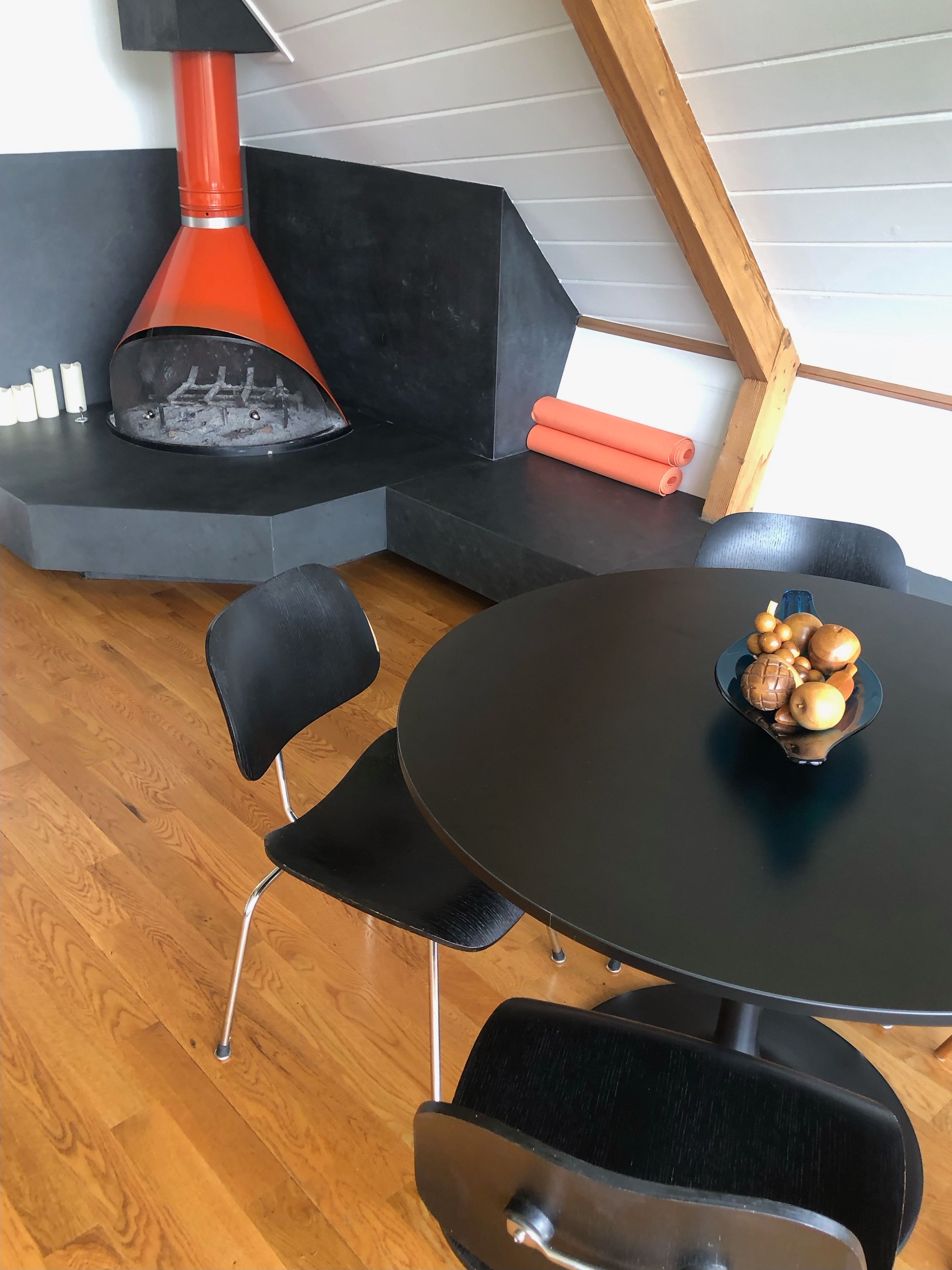 A modern interior with a black round table, black chairs, and a red fireplace.