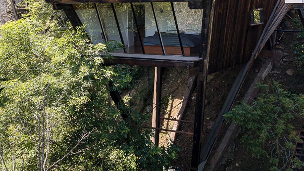 A two-story wooden house with a sloped roof and a balcony. - Architectural Marvel in Hollywood Hills with Views (Los Angeles)