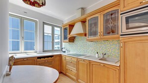 Een keuken met houten kastjes, een groot raam en een betegelde achterwand.