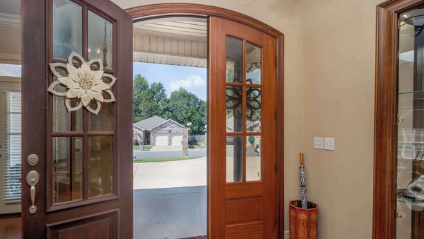 Puerta de madera con paneles de vidrio y un diseño floral decorativo.