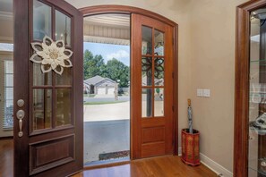 A wooden front door with glass panels and a decorative flower design.