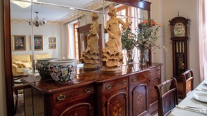 Un comedor con mesa de madera, sillas, un espejo grande y un reloj en la pared.