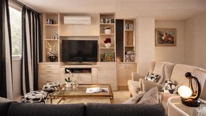 Una sala de estar moderna con un sofá, una mesa de centro, televisor, estantería y objetos decorativos.