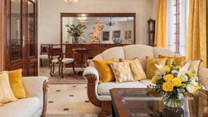 Una sala de estar con sofá, sillas, mesa de centro, candelabro y espejo.