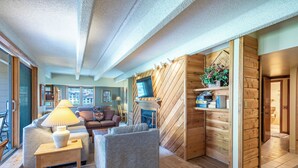 Een gezellige woonkamer met een open haard, houten wanden en een comfortabele zithoek.