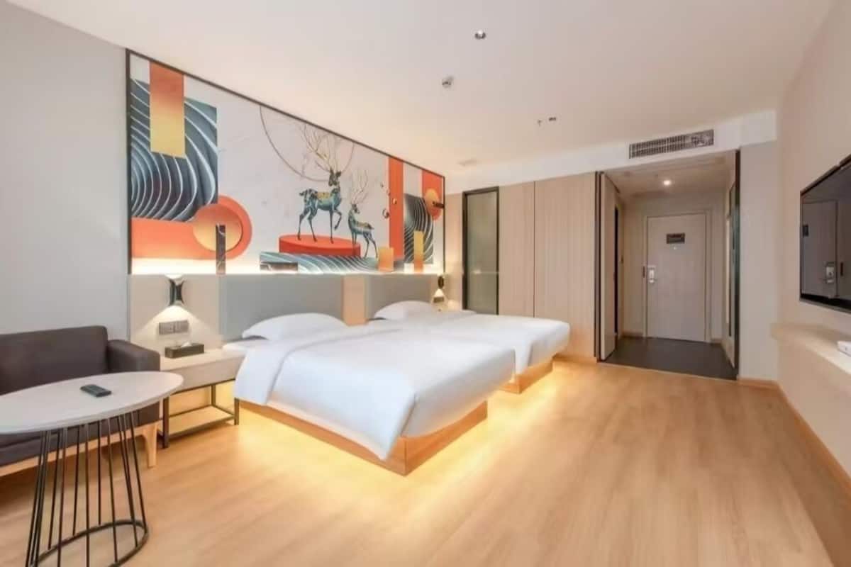 A hotel room with a large bed, a desk, a chair, and a TV.
