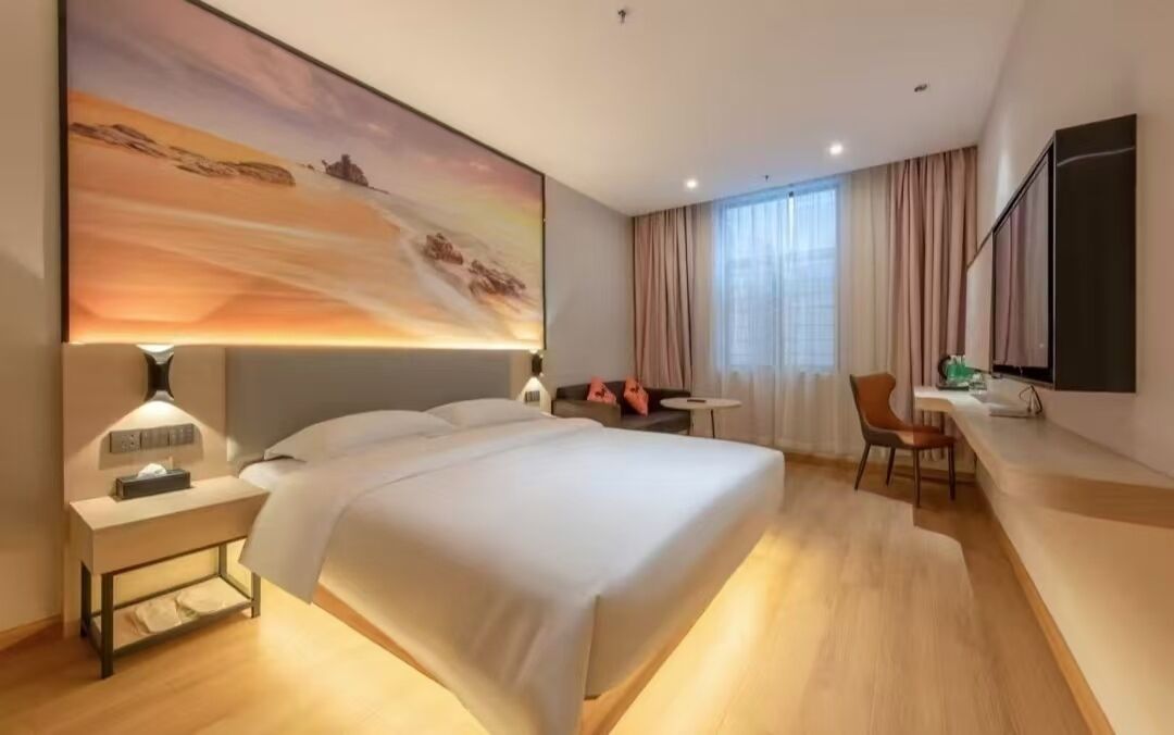 Una habitación de hotel moderna con una cama grande, un escritorio, una silla y un cuadro en la pared.
