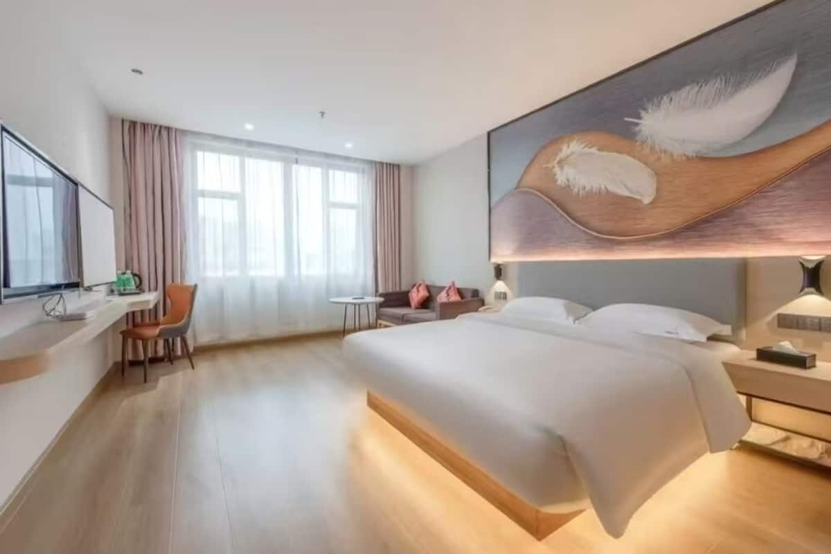 A modern hotel room with a large bed, a desk, and a chair.