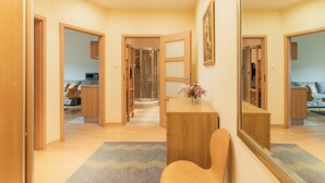 Um interior moderno com uma escrivaninha de madeira, uma cadeira, um espelho e um corredor que dá para um quarto.