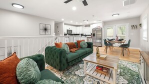 Ein modernes Wohnzimmer mit einem grünen Sofa, einem Couchtisch und einem Essbereich mit Tisch und Stühlen.