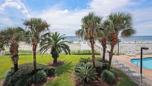 A pool area with palm trees and a view of the beach. - Direct Gulf Front 2BR/2BA condo (Gulf Shores)