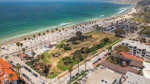 Vista aérea de una zona costera con playa, estacionamientos y edificios residenciales.