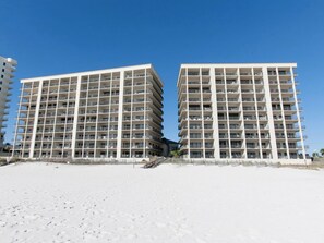 Ett hotell vid stranden med flera våningar, balkonger och en klar himmel.