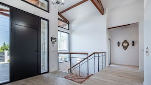 A modern interior with a wooden staircase, a black door, and a view of the outside. - Contemporary rural villa with large wooden beams with artistic accents (parracheira, Arrabal)