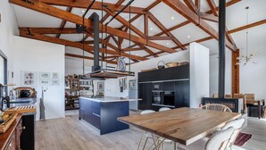 A spacious kitchen with a central island, wooden beams, and modern appliances. - Contemporary rural villa with large wooden beams with artistic accents (parracheira, Arrabal)