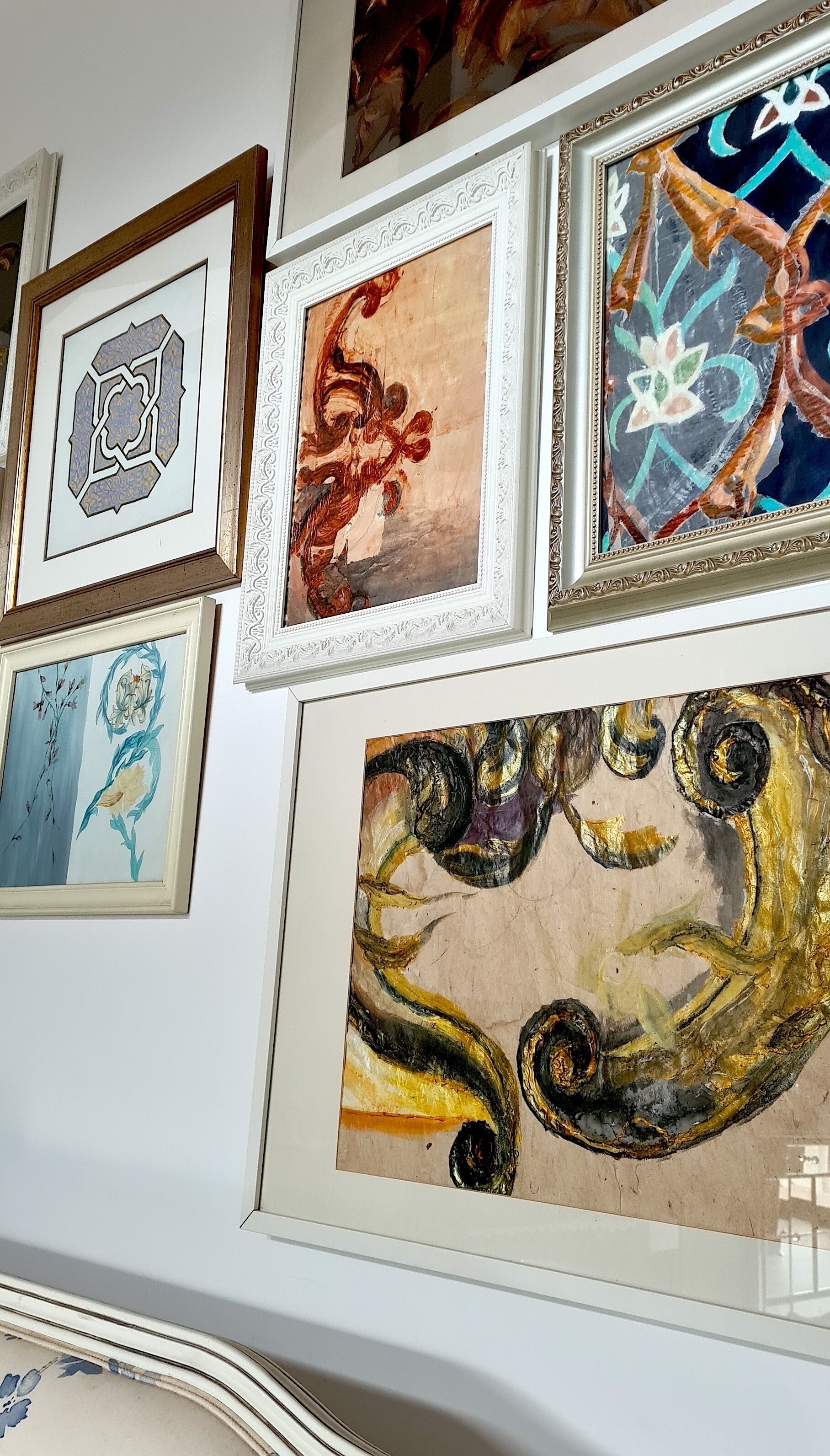 A wall with various framed artworks, including geometric patterns and abstract designs.