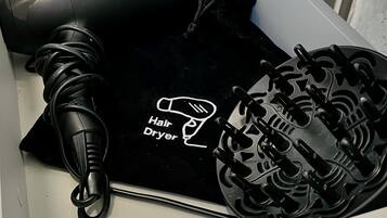 A black hair dryer with a cord, placed in a white drawer.