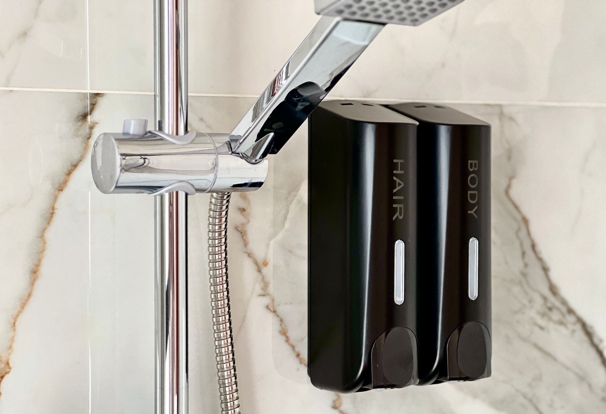 A bathroom with a modern shower setup, including a chrome faucet and a handheld showerhead.