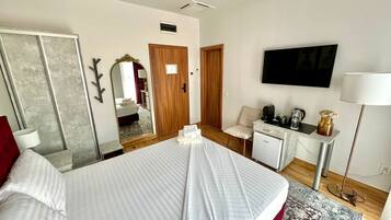 Habitació d'hotel amb un llit, una taula de treball amb una cadira, un televisor i un mirall.