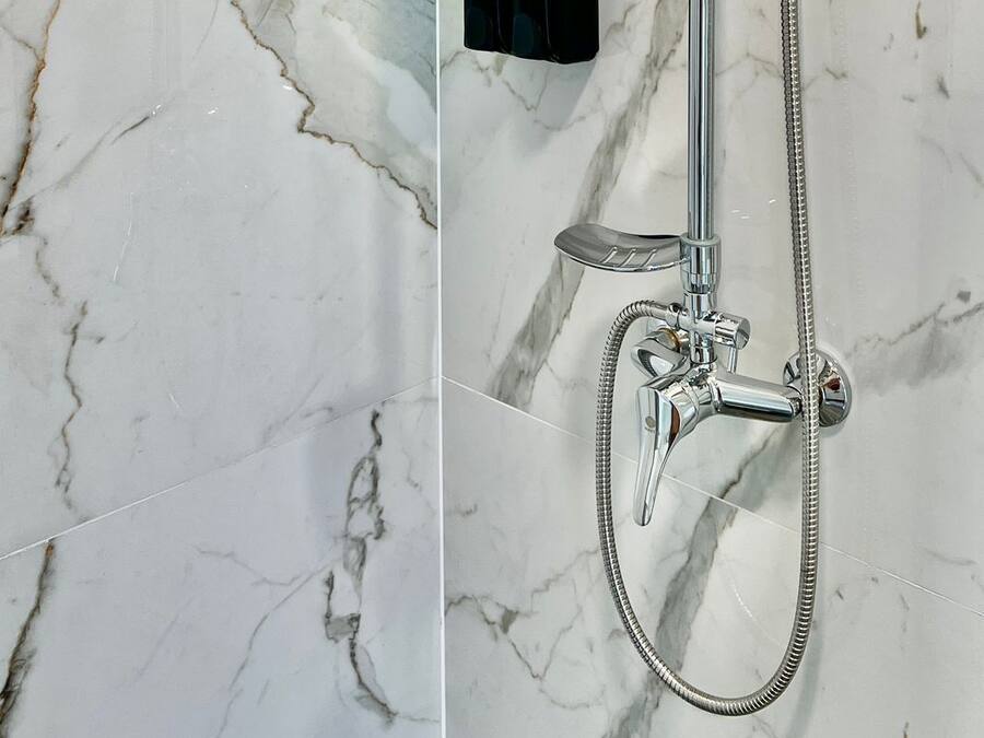 A modern shower with a handheld showerhead, a fixed showerhead, and a handheld shower hose.