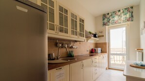 A kitchen with a stainless steel refrigerator, beige cabinets, a sink, and a window overlooking a balcony. - Red by Grand Apartments (Sopot)