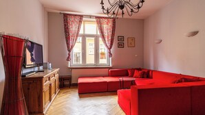 A living room with a red sofa, wooden cabinet, and a television. - Red by Grand Apartments (Sopot)