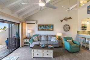 A living room with a sofa, a coffee table, a teal armchair, a clock, and a painting.