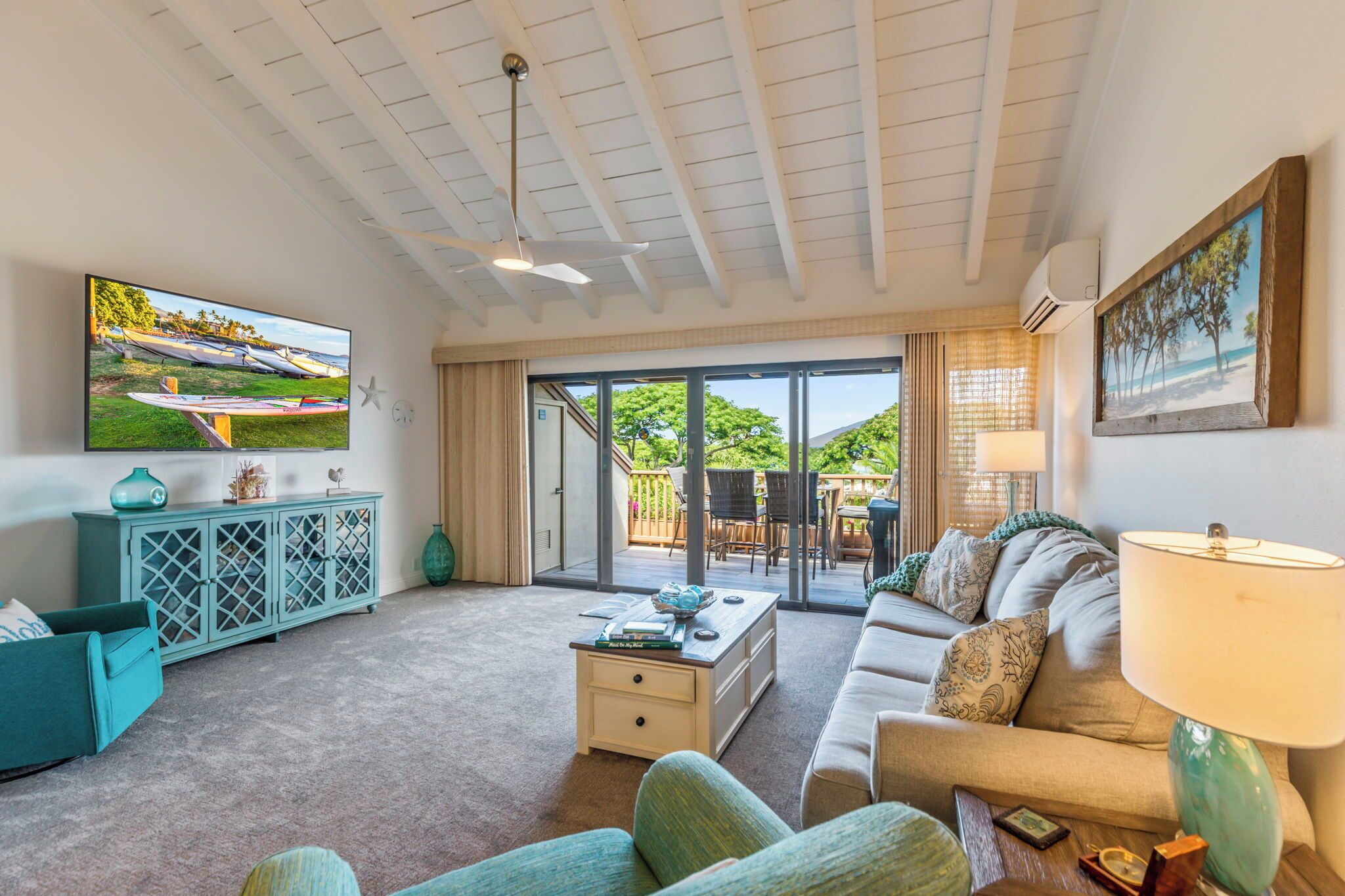 Sala de estar con televisor, sofá, mesa de centro y vistas al exterior.