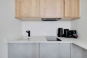 Eine moderne Küche mit Holzschränken, einer weißen Arbeitsplatte, einem Spülbecken und einer Kaffeemaschine.