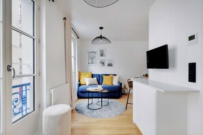 Ein modernes Wohnzimmer mit einem blauen Sofa, einem runden Couchtisch und einem an der Wand befestigten Fernseher.