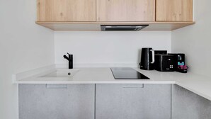 A modern kitchen with wooden cabinets, a white countertop, a sink, and a coffee maker. - Beautiful Cozy Apartment - 1 BDR/4P - Gare de Lyon / AC (Paris)