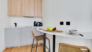 A modern kitchen with white cabinetry, a round dining table, and a wicker chair. - Beautiful Cozy Apartment - 1 BDR/4P - Gare de Lyon / AC (Paris)