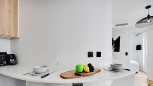 A modern kitchen with a white island, wooden chairs, and a fruit board. - Beautiful Cozy Apartment - 1 BDR/4P - Gare de Lyon / AC (Paris)