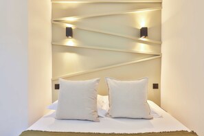 Ein Hotelzimmer mit einem Bett, zwei Kissen und einer Wandleuchte.