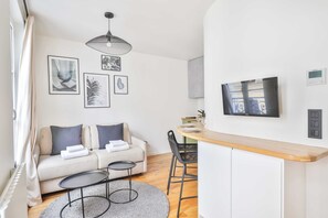 Una sala moderna con sofá, una mesita redonda y un comedor con mostrador de madera y sillas.