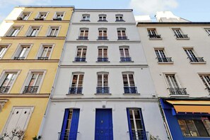 A multi-story building with a central blue door, white and yellow facades, and balconies with black railings. - Cosy Studio - 4P/1B  - Gare de Lyon / Bastille (Paris)