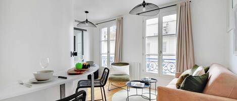 A modern living space with a dining area, a sofa, and a round coffee table.