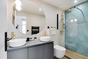 Un bagno moderno con due lavandini, uno specchio grande e una doccia.