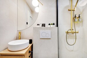 A modern bathroom with a white sink, gold fixtures, and a large mirror. - Magnific location - 1BDR/4P - Gare de Lyon (Paris)