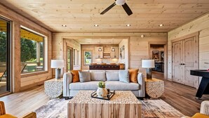 A spacious living room with a wooden ceiling, a sofa, two side tables, and a coffee table.