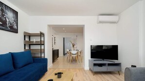 A modern living room with a sofa, TV, coffee table, and a dining area in the background. - Air-conditioned Studio for 6 Persons | 600 m from the Market Square (Wrocław)