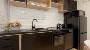 A modern kitchen with black cabinetry, a stainless steel sink, a built-in oven, and a microwave. - Air-conditioned Studio for 6 Persons | 600 m from the Market Square (Wrocław)