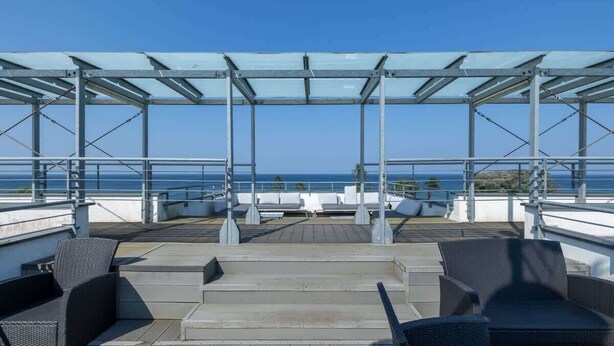 A rooftop terrace with outdoor seating and a view of the sea.