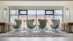 A spacious room with three modern chairs, large windows, and a patterned floor.