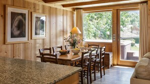 A wooden interior with a dining area, granite countertop, and large windows with curtains. - Chalet Scierie - luxury chalet with hot tub (Chamonix-Mont-Blanc)