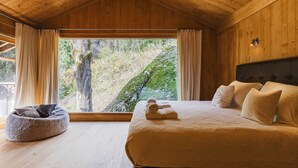 A wooden cabin bedroom with a large window, a bed, and a bean bag chair. - Chalet Scierie - luxury chalet with hot tub (Chamonix-Mont-Blanc)