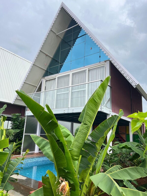 A modern building with a triangular roof and a swimming pool in the foreground. - Sakhi Lakeview Resort (Hyderabad)