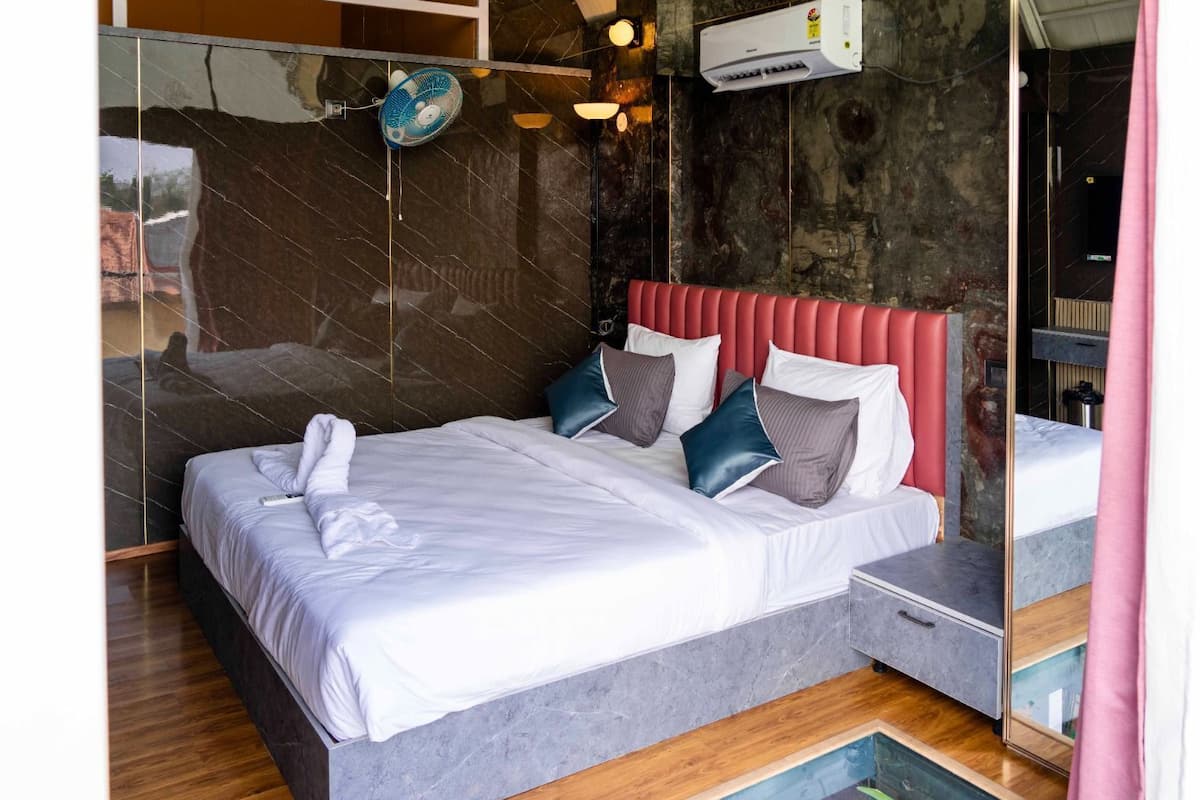Quarto moderno com cama, mesa de cabeceira, espelho e ar-condicionado fixado na parede.