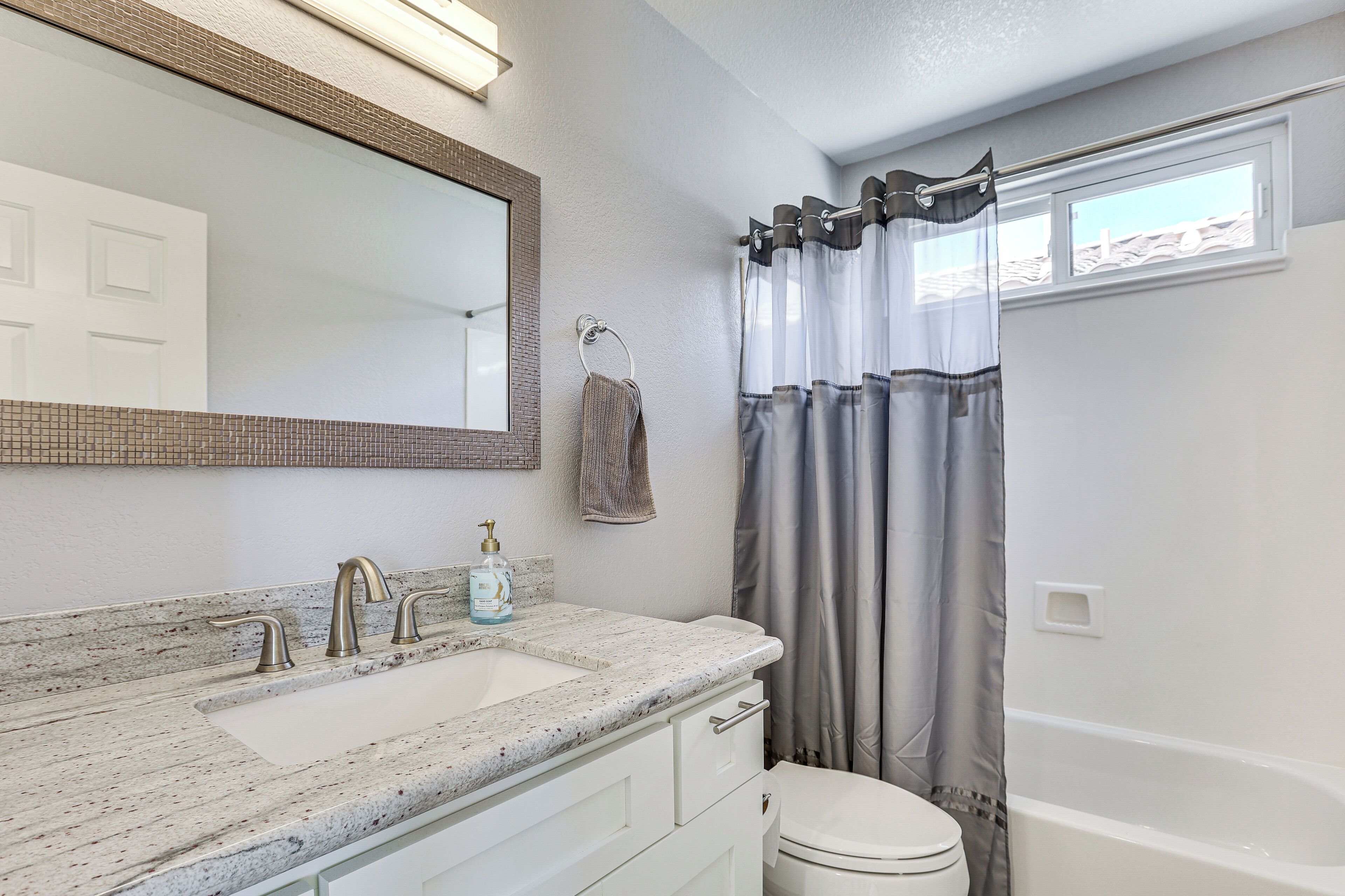 A bathroom with a sink, mirror, towel rack, and a shower curtain.