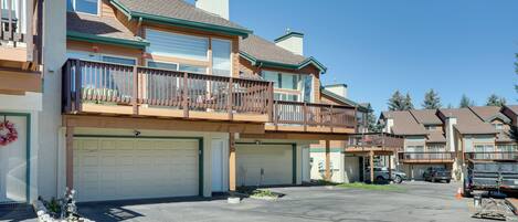 A multi-story residential building with a garage, a balcony, and a small garden area.
